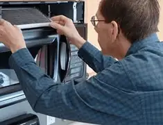 Appliance repair technician replacing a microwave vent filter in Phoenix, AZ