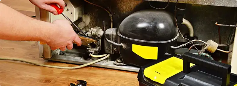 Refrigerator repair technician fixing the compressor and wiring in Glendale, AZ