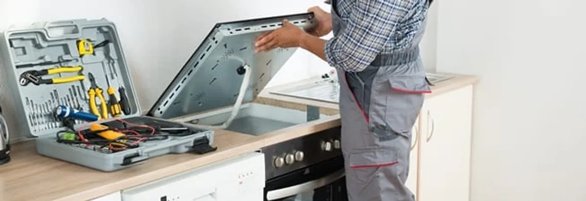 Cooktop repair technician lifting a built-in stovetop for service in Phoenix, AZ
