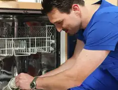 Dishwasher repair technician inspecting and servicing an open dishwasher in Phoenix, AZ