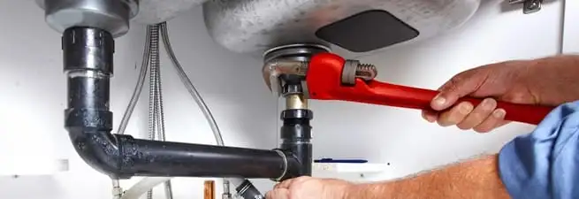 Garbage disposal repair technician tightening the sink drain and disposal connection in Phoenix, AZ