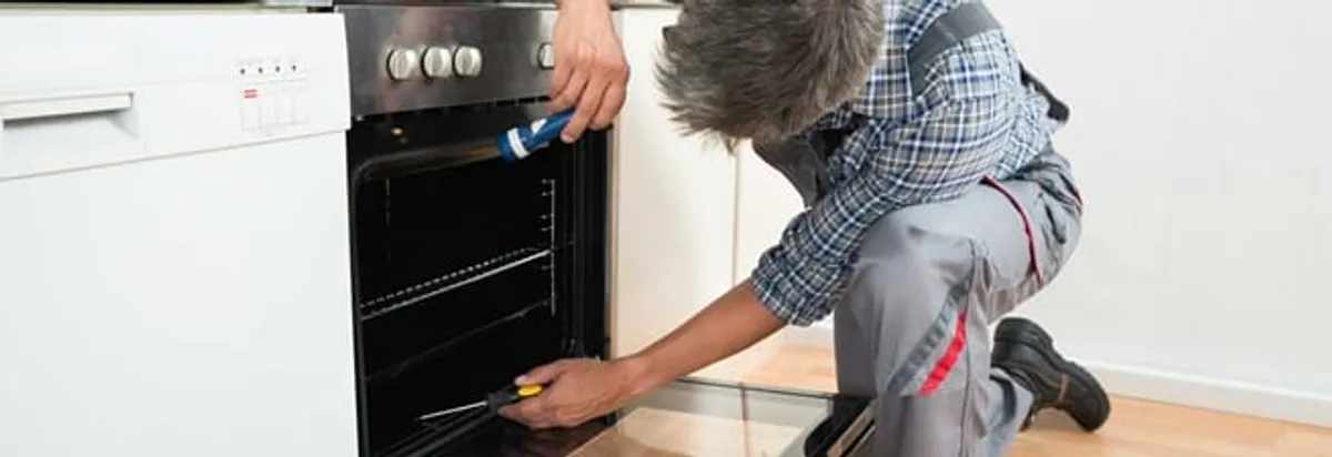 Oven repair technician inspecting and servicing an electric oven in Phoenix, AZ