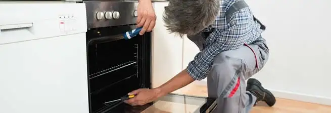 Oven repair technician inspecting and servicing an electric oven in Phoenix, AZ