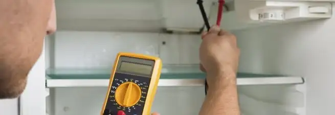 Refrigerator repair technician testing electrical components with a multimeter in Phoenix, AZ