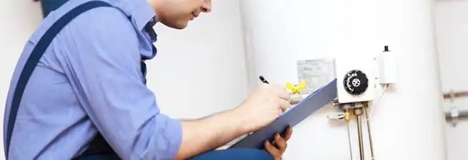 Water heater repair technician inspecting the unit and recording service notes in Phoenix, AZ